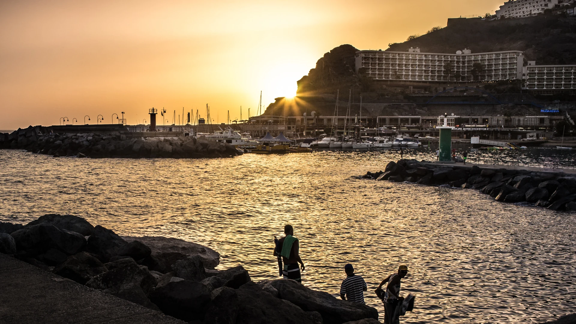 Sunset over Puerto Rico's harbour on Gran Canaria, with a hotel on the cliff above the marina