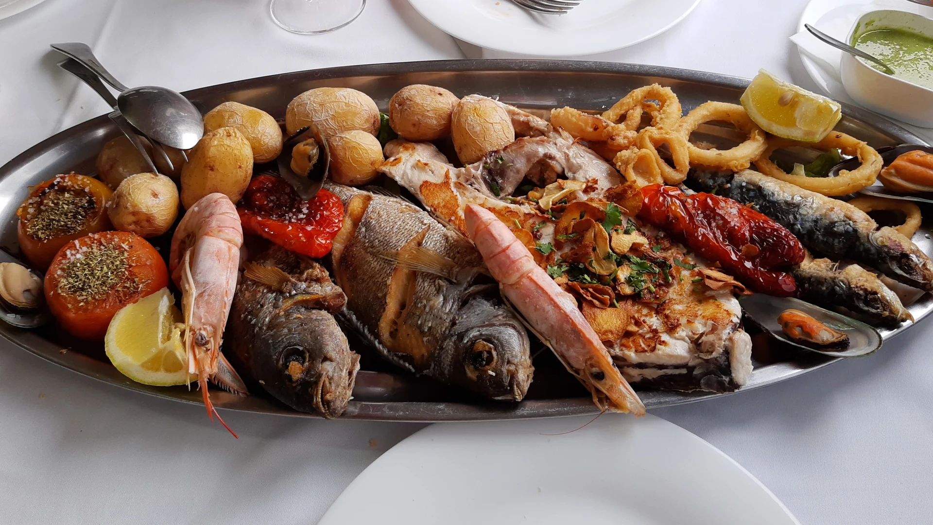 A platter of grilled fish, prawns, squid rings and wrinkled potatoes with green mojo at a restaurant in Puerto de las Nieves, Gran Canaria