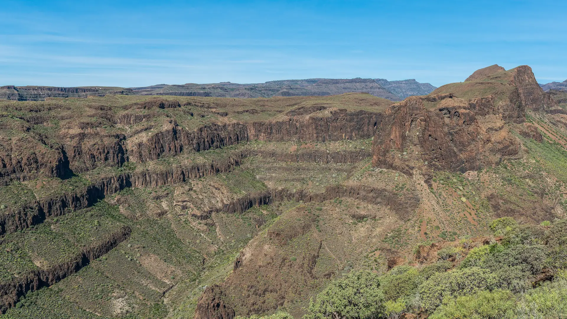 Layered volcanic cliffs and scrub-covered slopes of the Barranco de Fataga in the interior of southern Gran Canaria