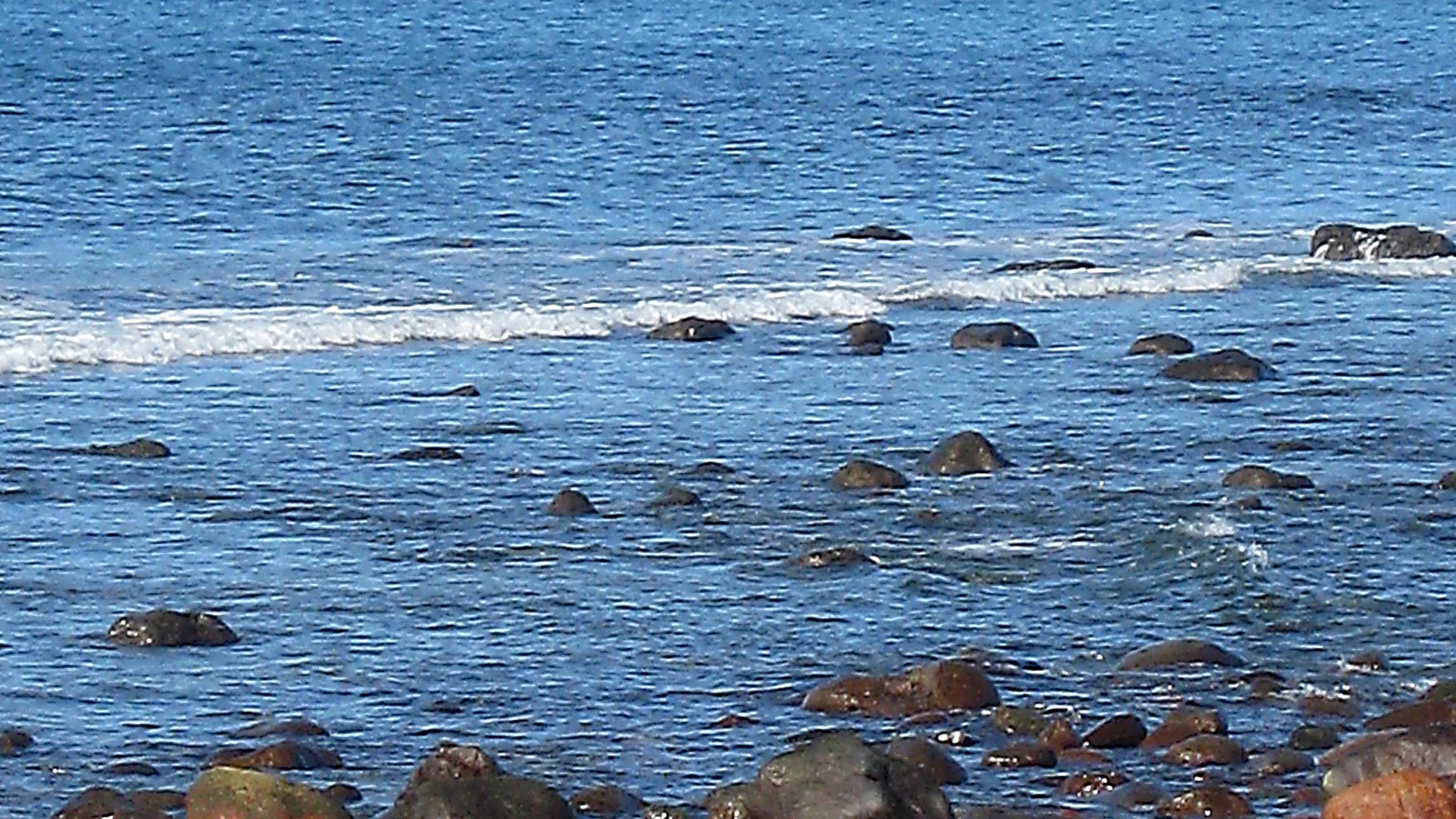 Clear Atlantic water breaking over volcanic rocks on the shore at Arguineguín, south-west Gran Canaria