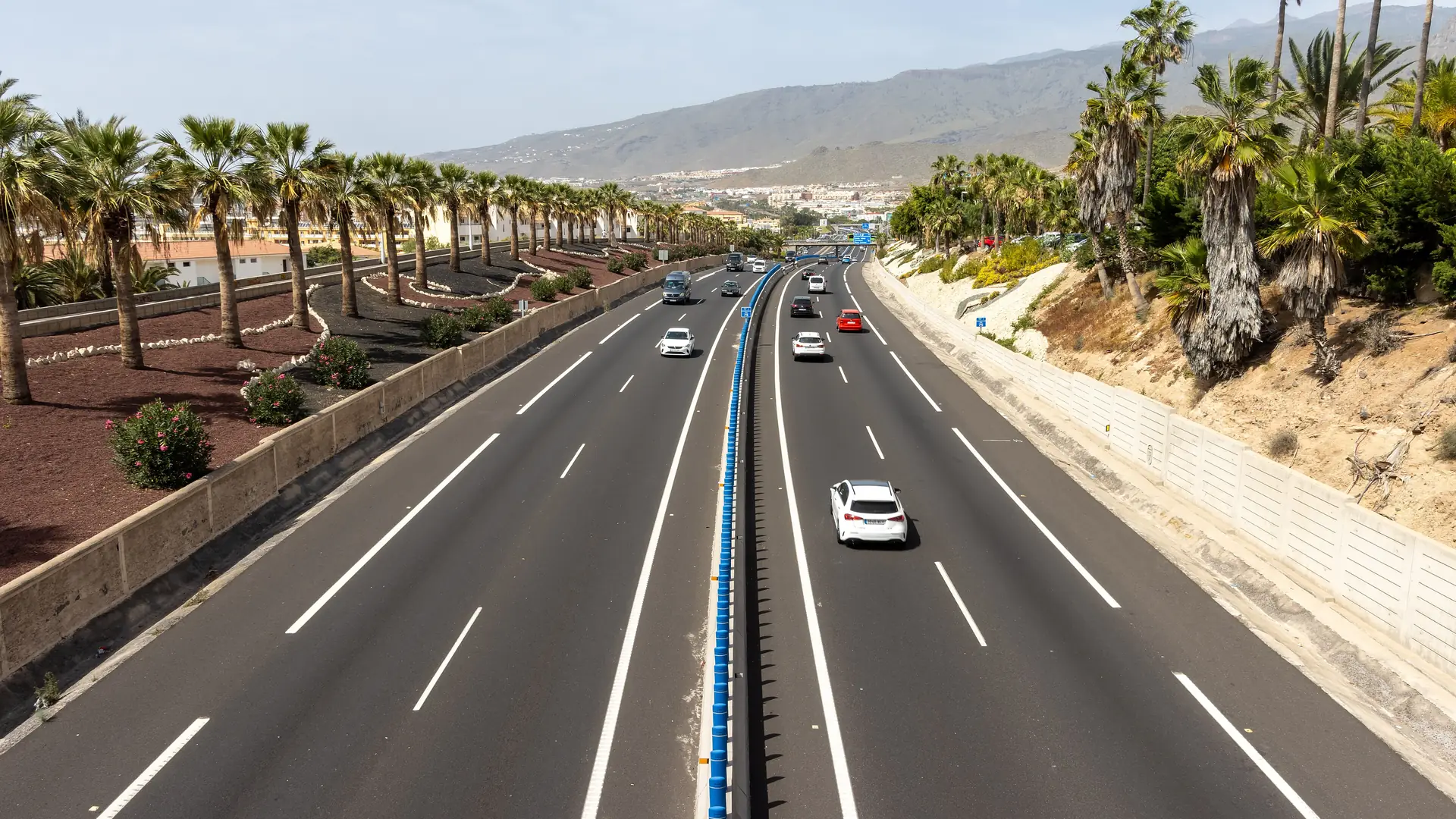 The TF-1 motorway running between palm-lined resorts in southern Tenerife, with the island's hills behind