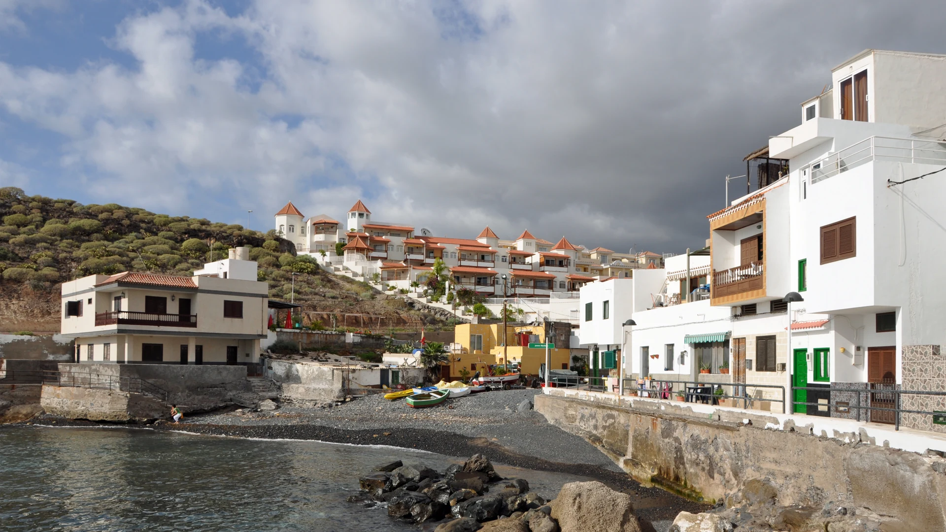Low white villas stepping up the hillside above the pebble cove at La Caleta, Adeje, in southern Tenerife