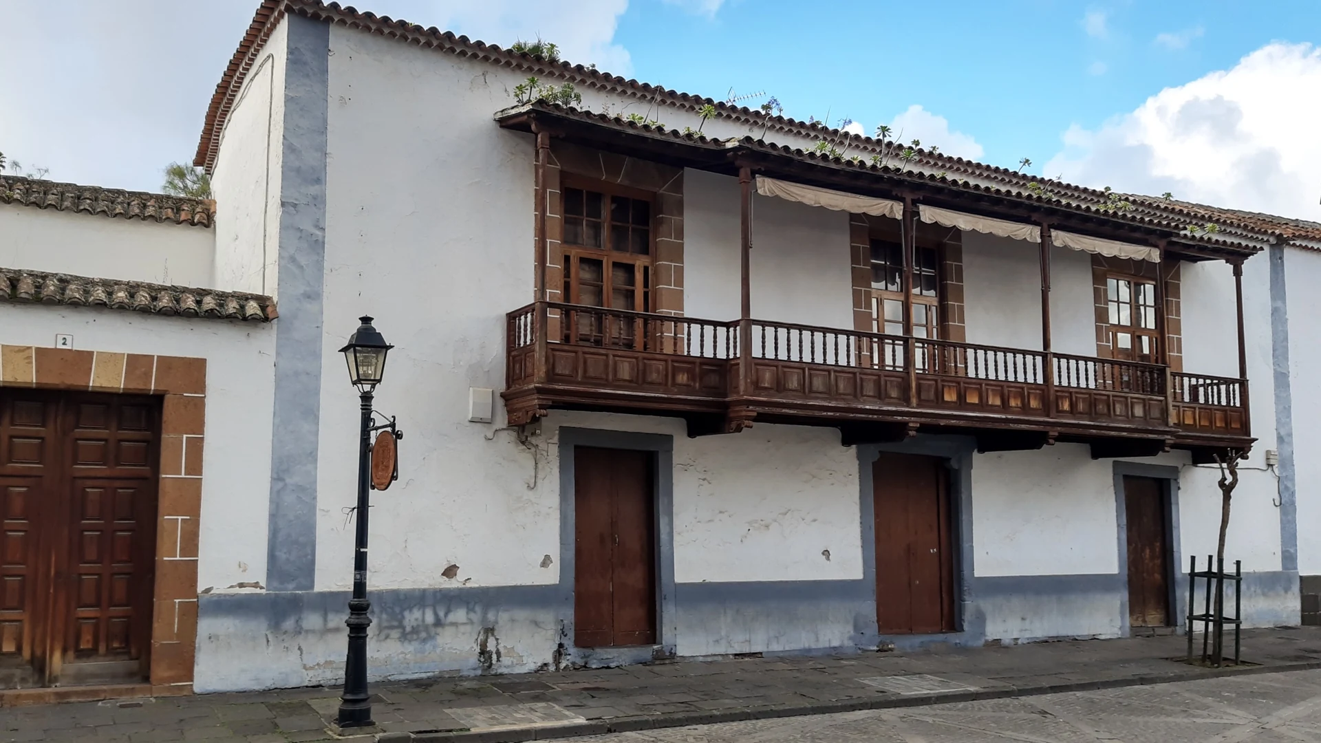 A whitewashed colonial house with a long carved wooden balcony on a street near the basilica in Teror, Gran Canaria