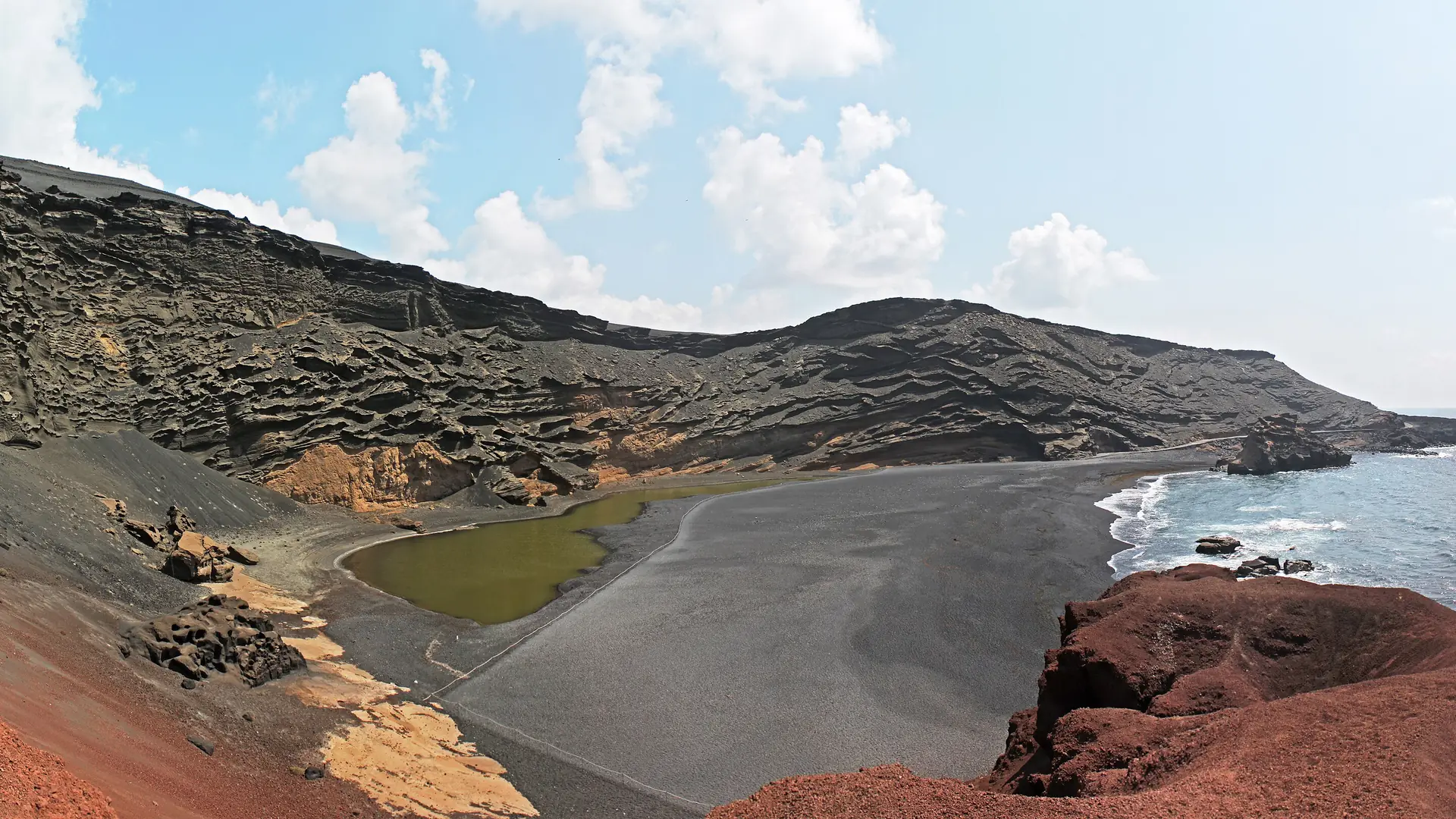 The green Charco de los Clicos lagoon and black-sand beach inside the volcanic crater at El Golfo, on Lanzarote's west coast